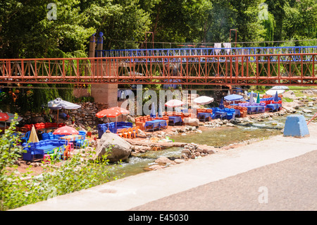 Kunststoff Terrasse Tische, Stühle und Sonnenschirme in den Restaurants am Ufer des Flusses Ourika, Ourika Valley, Atlas, Marokko Stockfoto