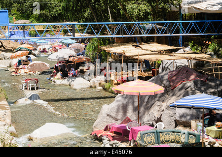 Kunststoff Terrasse Tische, Stühle und Sonnenschirme in den Restaurants am Ufer des Flusses Ourika, Ourika Valley, Atlas, Marokko Stockfoto