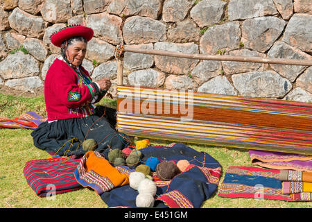 Ältere Frau mit Hut, Quechua-Indianer in traditioneller Kleidung, sitzen auf dem Boden auf der Bahre ein Webstuhl funktioniert Stockfoto