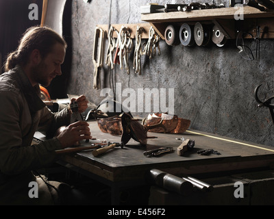 Schmiede arbeiten mit Kupfernieten in Werkstatt Stockfoto