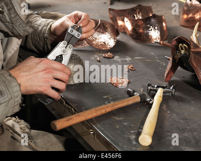 Bild der Schmiede Hände arbeiten mit Kupfernieten beschnitten Stockfoto