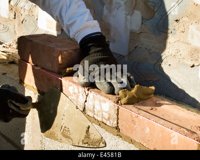 Selbstbau-Haus, Hände der Maurer legt Brick und block Stockfoto