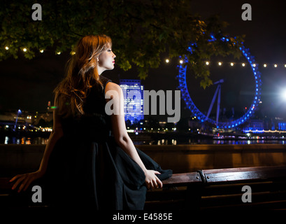 Junge Frau Blick auf London Eye in der Nacht, London, UK Stockfoto