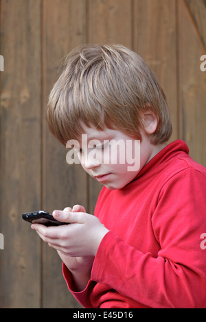 kleiner Junge Schreiben einer Kurzmitteilung auf dem Handy Stockfoto