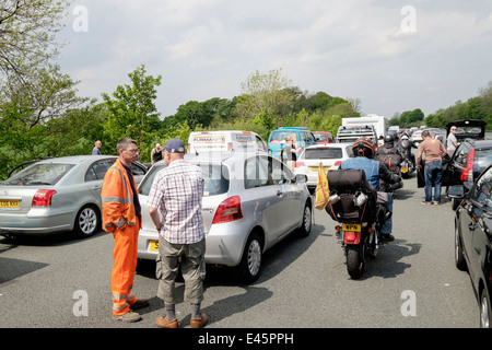 Motorräder fahren Reiten durch stehende Fahrzeuge im Stau mit Menschen stehen auf Fahrbahn auf der Autobahn M6. Lancashire England Großbritannien Stockfoto