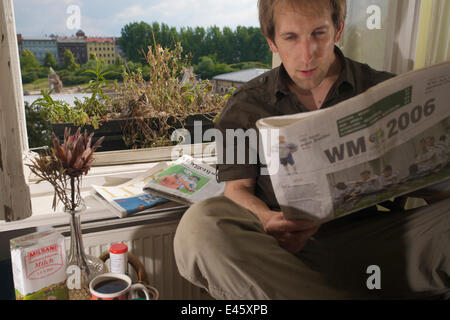 Fotograf Florian Mollers frühstücken neben einer weiblichen Stockente (Anas Platyrhynchos) nisten in Fenster-Box von einem 4. Stock Wohnung, Berlin, Deutschland, Juni. Modell veröffentlicht Stockfoto