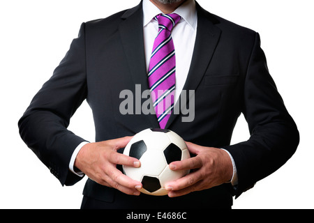 Business-Mann im dunklen Anzug und Krawatte hält einen Fußball Stockfoto