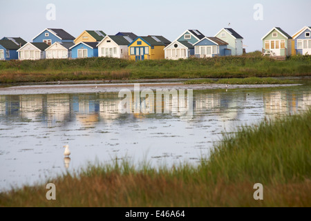 Strandhütten, die sich im Wasser von Hengistbury Head, Mudeford Spit, Christchurch, Dorset UK im Abendlicht im Juli spiegeln Stockfoto