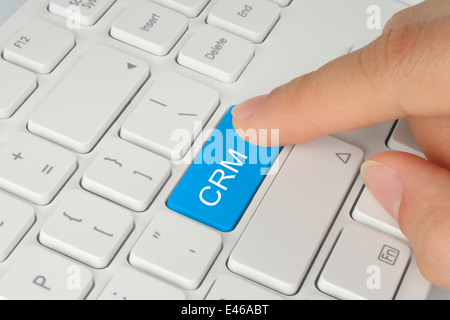 Hand drücken Blau CRM (Customer Relationship Management) Taste auf der Tastatur Weiß Hintergrund Stockfoto