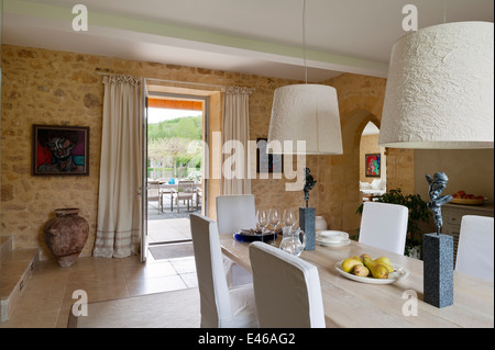 Esszimmer mit abstrakter Malerei an der Wand und Esstisch mit zwei Lampenschirmen Stockfoto