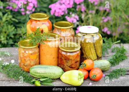 Canning bewahrt hausgemachten Snack Tomate Tomaten Gurken Gurken Aubergine Gläser Deckel Topf Vorbereitung Essen Lager Sommer Tag Schreibtisch Stockfoto