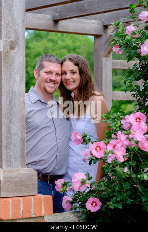 Eine Konzepte Bild einer glücklichen, liebevollen Paar in ihrem 20s für Engagement Bilder in einem wunderschönen Park, umgeben von bunten Blumen darstellen. USA. Stockfoto