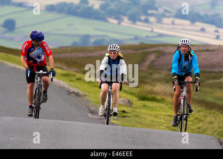 Grinton, Yorkshire Dales, Großbritannien, 3. Juli 2014. Drei Radfahrer auf dem Anstieg von Grinton auf der Route nach Leyburn. Tausende von Radfahrern waren in den Yorkshire Dales unterwegs auf der Route des Grand Depart. Die Straßen und Felder, die dem Parken und Campen zugeordnet sind, füllen sich nun in Vorbereitung auf die Veranstaltung am Samstag aus. Stockfoto