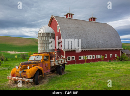 Palouse, Whitman County, WA: Vintage-Tieflader vor roten Scheune und Silo im Sommer, Palouse Land Stockfoto