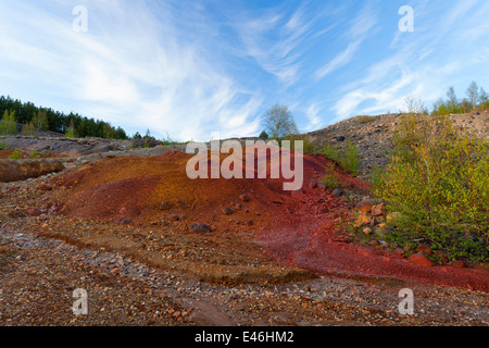 Stein und Erde wiederum starke rostige, rote, lila und braune Farben als Abfluss aus nahe gelegenen Bergbau Operationen fließt über die Landschaft. Stockfoto