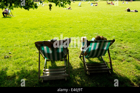 Ein paar faulenzen im Liegestuhl am Londoner St. James's Park an einem sonnigen Tag, England Stockfoto