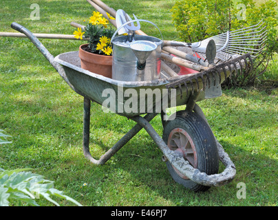 Gartengeräte in einer Schubkarre mit Topfblumen Stockfoto