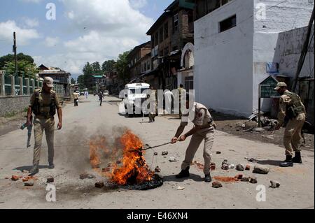 Srinagar, Kaschmir Indien kontrollierten. 4. Juli 2014. Indische Polizisten entfernen einen brennenden Reifen und Ziegel von der Straße während eines Streiks in Srinagar, Sommer in der Hauptstadt von Indien kontrollierten Kaschmir, am 4. Juli 2014. Behörden verhängten Beschränkungen in Teilen von Srinagar am Freitag während Separatisten für einen Schlag gegen indische Premierminister Narendra Modi Besuch in Indien kontrollierten Kaschmir nennen. Bildnachweis: Javed Dar/Xinhua/Alamy Live-Nachrichten Stockfoto