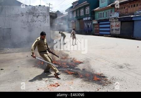 Srinagar, Kaschmir Indien kontrollierten. 4. Juli 2014. Indische Polizisten entfernen einen brennenden Reifen und Ziegel von der Straße während eines Streiks in Srinagar, Sommer in der Hauptstadt von Indien kontrollierten Kaschmir, am 4. Juli 2014. Behörden verhängten Beschränkungen in Teilen von Srinagar am Freitag während Separatisten für einen Schlag gegen indische Premierminister Narendra Modi Besuch in Indien kontrollierten Kaschmir nennen. Bildnachweis: Javed Dar/Xinhua/Alamy Live-Nachrichten Stockfoto