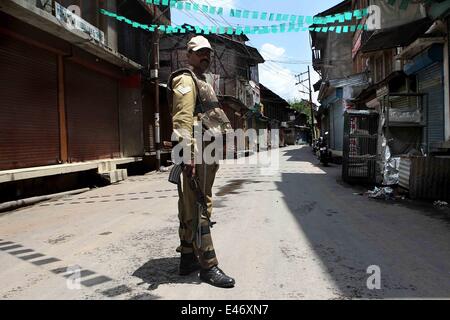 Srinagar, Kaschmir Indien kontrollierten. 4. Juli 2014. Eine indische paramilitärischer Soldat steht Wache in einem geschlossenen Markt während eines Streiks in Srinagar, Sommer in der Hauptstadt von Indien kontrollierten Kaschmir, am 4. Juli 2014. Behörden verhängten Beschränkungen in Teilen von Srinagar am Freitag während Separatisten für einen Schlag gegen indische Premierminister Narendra Modi Besuch in Indien kontrollierten Kaschmir nennen. Bildnachweis: Javed Dar/Xinhua/Alamy Live-Nachrichten Stockfoto