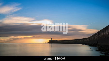 Atemberaubenden Sonnenaufgang über dem Meer mit Leuchtturm und Hafen Wand Stockfoto