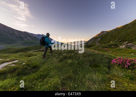 Männliche Wanderer mit Rucksack, Wanderkarte bei Sonnenaufgang in der Italiener beobachten französische Alpen. Stockfoto