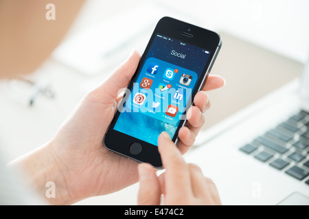 Frau, die auf social Media-Anwendungen auf einem brandneuen schwarz Apple iPhone 5 s Stockfoto