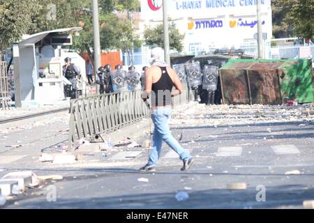 Shufat, annektierte Ost-Jerusalem, Israel. 4. Juli 2014. Ein einsamen palästinensischen Jugendlichen steht gegenüber schwer bewaffneten israelischen Streitkräfte. Im Anschluss an die Beerdigung von Muhammed Abu Khdeir Zusammenstöße brach fast sofort nach. Palästinensische Jugendliche aus dem Dorf schleuderten Felsen auf die israelischen Streitkräfte. Spannungen haben wochenlang nun seit der Tötung von drei israelischen Jugendlichen und jetzt dieses scheinbare Rache töten eskaliert. Bildnachweis: Anna Ferensowicz / pazifische Presse/Alamy Live News Stockfoto