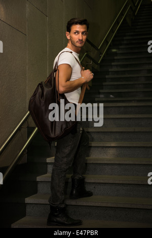 Hübscher junger Mann stehend mit big-Bag auf Treppe Schritte, wegschauen Stockfoto