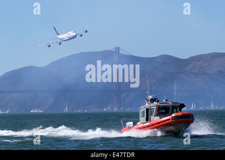 United Airlines Boeing 747-400 jagt ein USCG Defender Klasse Antwort Boot (RB-S) entlang der Küste von San Francisco Stockfoto