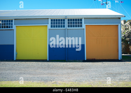 Orange und gelbe Türen auf einem blau lackierten Lager in Fremantle, Western Australia. Stockfoto