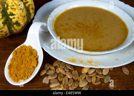 Curry-Kürbis-Suppe in weiße Schüssel mit Curry-Pulver, Kürbis und Kürbiskerne Stockfoto