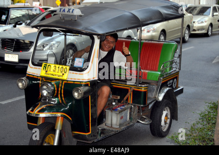 BANGKOK, THAILAND: Eine lächelnde Tuk-Tuk Taxifahrer sitzen im Verkehr auf belebten Thanon Rama ich im Zentrum von Bangkok Stockfoto