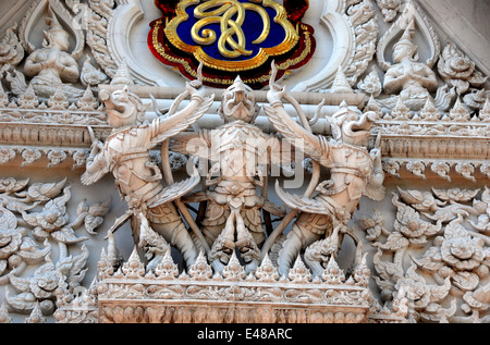 BANGKOK, THAILAND: Ein Trio von geschnitzten Aponsi Figuren mit Blumenschmuck und Drachen schmückt ein Tympanon am Wat Hua Lamphong Stockfoto