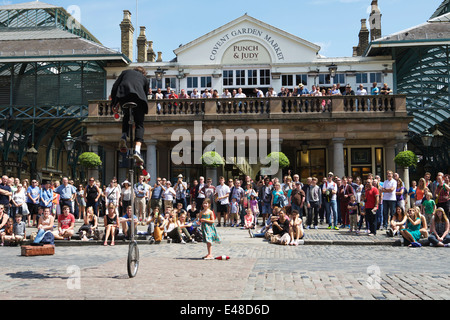 Straße Entertainer auf einem Einrad, Publikum und Punch & Judy Pub, Covent Garden Piazza, London, UK Stockfoto