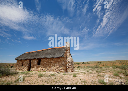 Einem historischen alten Steinhaus stehen in der trockenen Wüste. Blauer Himmel und weiße Wolken. Stockfoto