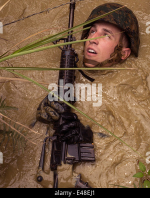 Ein US-Marine schwebt durch stehendes schlammiges Wasser wie er Konzertina Draht im Dschungel Ausdauer Verlauf bei Jungle Warfare Training Center Camp Gonsalves 20. Juni 2014 in Okinawa, Japan vermeidet. Stockfoto