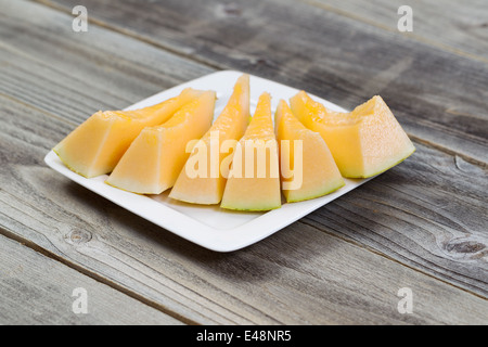 Detailansicht einer frisch geschnittenen Melonenscheiben auf weißen Teller auf rustikalen Holz Stockfoto