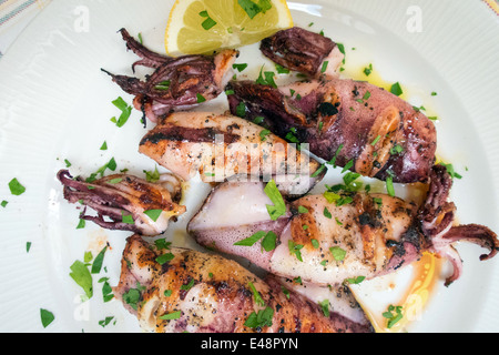 Gegrillter Tintenfisch auf Teller mit Zitrone und Petersilie Stockfoto