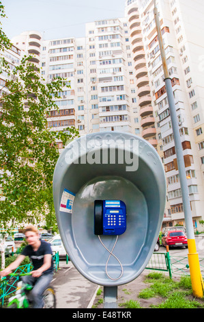 Kiew/UKRAINE - 16. Mai 2010 - A öffentliches Telefon (Taxophone) in der Stadt Kiew in der Ukraine. Ein Junge geht mit dem Fahrrad hindurch. Stockfoto