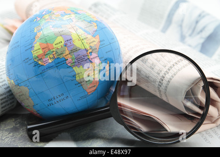 Globus und Lupe über Zeitungen Stockfoto