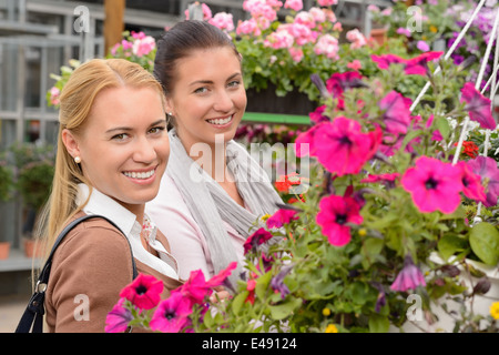 Zwei Kunden der Frau im Garten-Center stehen zwischen bunten Blumen Stockfoto