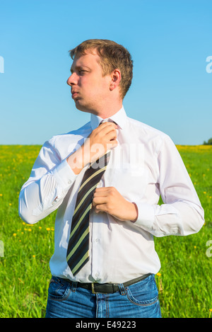 Manager passt seine Krawatte in einem grünen Feld Stockfoto