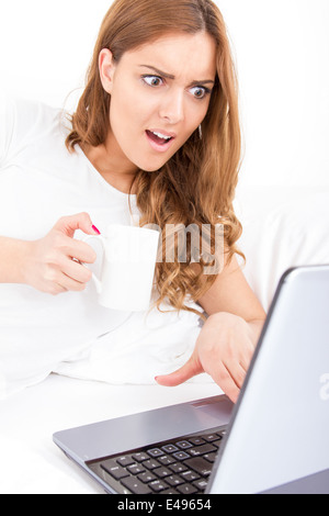 überrascht besorgt Frau auf der Suche im Bildschirm des Laptop-Computer immer schlechte Informationen beim Kaffeetrinken Stockfoto