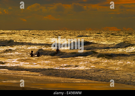 Gruppe von Personen, die während des Sonnenuntergangs am Baltischen Meer baden. Katy Rybackie, Pommern, Polen. Stockfoto