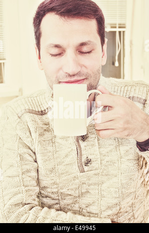 Gut, auf der Suche nach Mann genießen Sie das Aroma von einer Tasse heißem Kaffee oder Tee während einer Pause lächelnd mit seinen Augen in Genuss geschlossen, Vintage Retro Effekt Stil Stockfoto