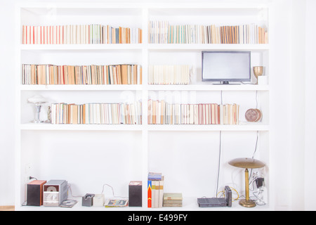 Weiß Wohnzimmer mit modernen Holz- weiß Regal und verschiedene Bücher innerhalb, häusliche Atmosphäre, Bibliothek Hintergrund in Innenräumen, sauber und modern eingerichtet Stockfoto