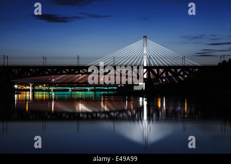 Beleuchtete Brücke bei Nacht und im Wasser gespiegelt. Swietokrzystki Brücke. Stockfoto