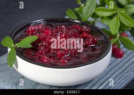Preiselbeerkonfitüre (Kronsbeeren) und Zweigen mit Blättern Stockfoto