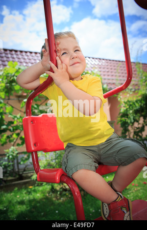ein Junge sitzt auf der Schaukel im Hinterhof Stockfoto